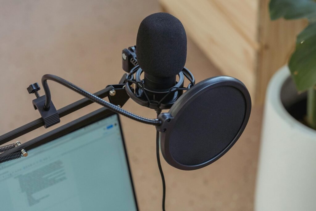 A modern podcast setup featuring a laptop and studio microphone on a desk, ideal for digital media production.